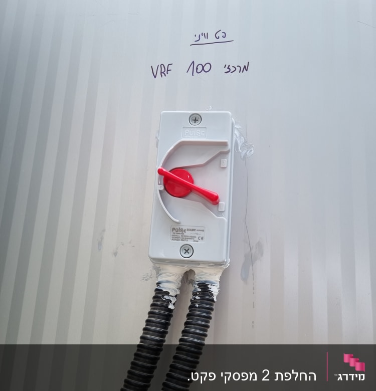 מתג חשמלי עם ידית אדומה ושני צינורות גמישים